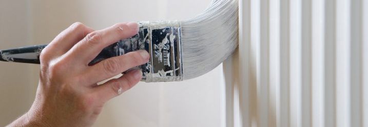 Hand streicht Heizkörper weiß
